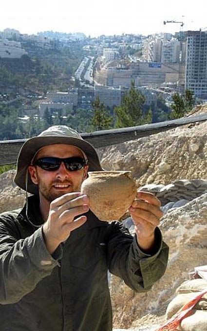 Alex Wigman, arqueólogo de la Autoridad de Antigüedades de Israel, muestra una pequeña vasija hallada en la tumba cananea descubierta en Jerusalén en el año 2014. (Shua Kisilevitz, Autoridad de Antigüedades de Israel)