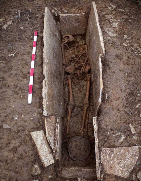 Uno de los esqueletos de esclavos romanos en la estructura de ataúd de piedra con una maceta (en la parte inferior del tiro) desenterrado en el lugar de enterramiento en Somerset, Inglaterra. (Arqueología de Wessex)