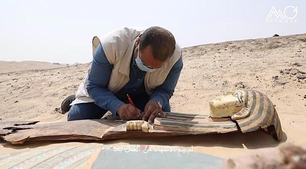 Otro de los antiguos sarcófagos egipcios desenterrados en el sitio arqueológico de Saqqara, siendo inspeccionado por un arqueólogo. (Ministerio de Turismo y Antigüedades de Egipto)