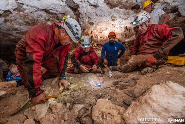 Arqueólogos del Instituto Nacional de Antropología e Historia (INAH) observan fragmentos de cerámica en una cueva, como parte del trabajo arqueológico que acompaña a la construcción de un polémico nuevo tren. (Oficina Península de Yucatán de la SAS-INAH)