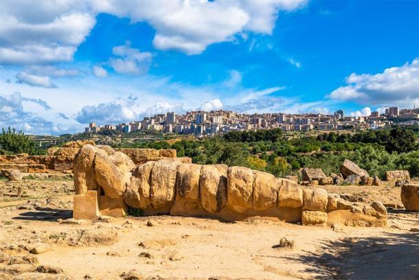 La estatua de Atlas acostada con la moderna ciudad italiana de Agrigento al fondo. (javarman / Adobe Stock)