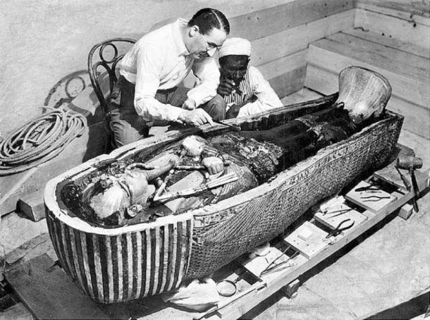 Howard Carter y un obrero egipcio examinan el tercer ataúd (el más interior) de Tutankamón hecho de oro macizo, dentro de la caja del segundo ataúd. (Dominio publico)