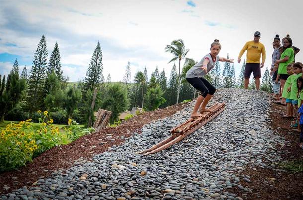 Un taller de enseñanza de trineos de lava de he'e holua usando un trineo de papa holua y bajando por una pista de trineos de kahua holua reconstruida. (Cortesía de Tom “Pohaku” Stone)